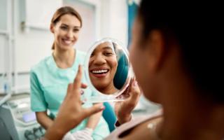 Image of a patient with dental nurse inspecting her white smile.