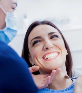 Image of a patient receiving treatment from her dentist, with a beaming smile.