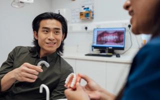Image of a male patient holding his Invisalign aligner with his dentist who is explaining the treatment.
