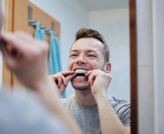 Image of a man at his home putting on teeth whitening trays.