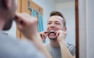 Image of a male putting on his teeth whitening trays.