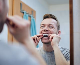 Image of male putting on his at-home teeth whitening braces.