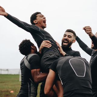 Image of a group of young boys playing rugby on a field.