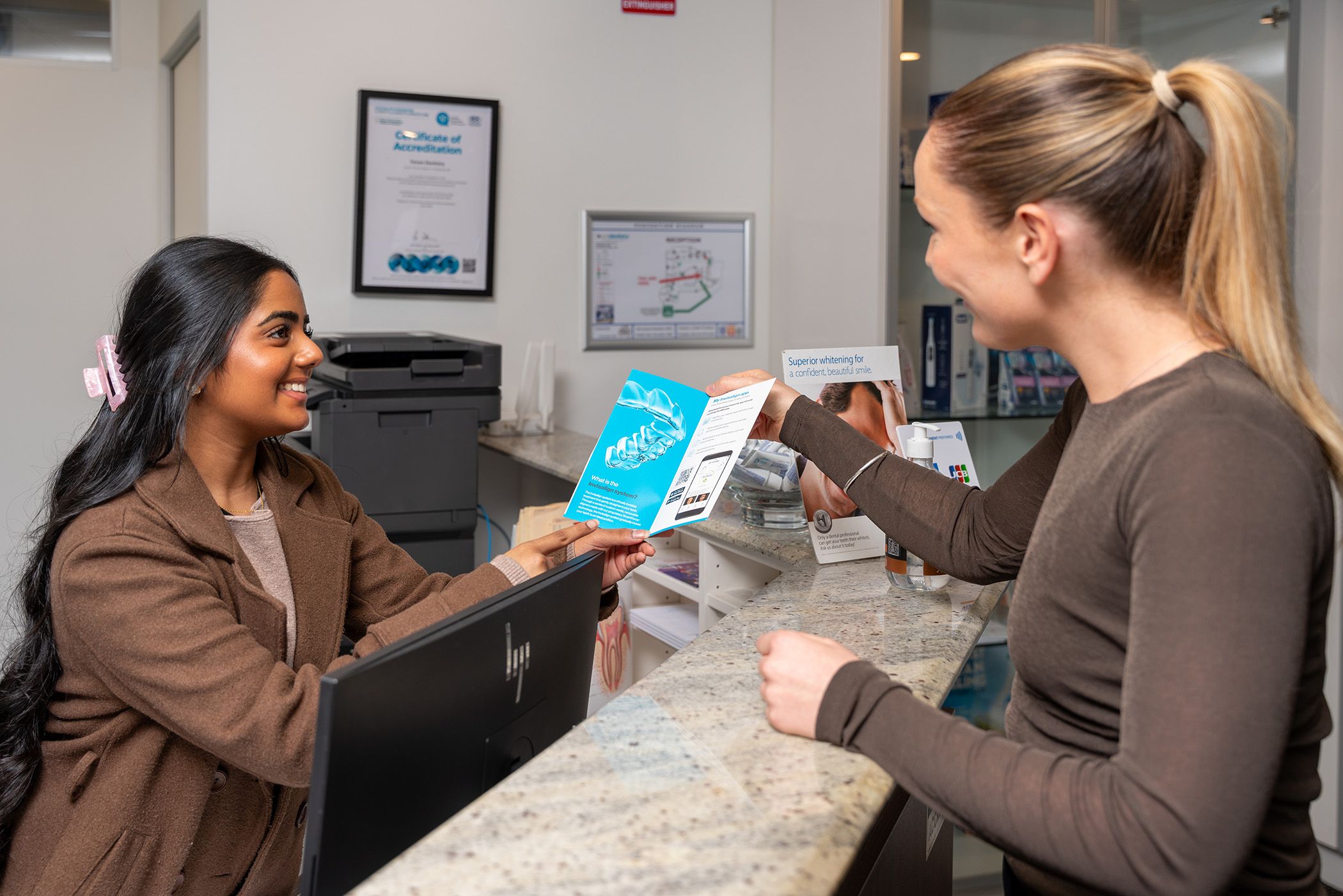Image of our receptionist showing her patient all the information to be prepared.