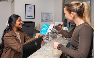 Image of our receptionist showing her patient all the information to be prepared.