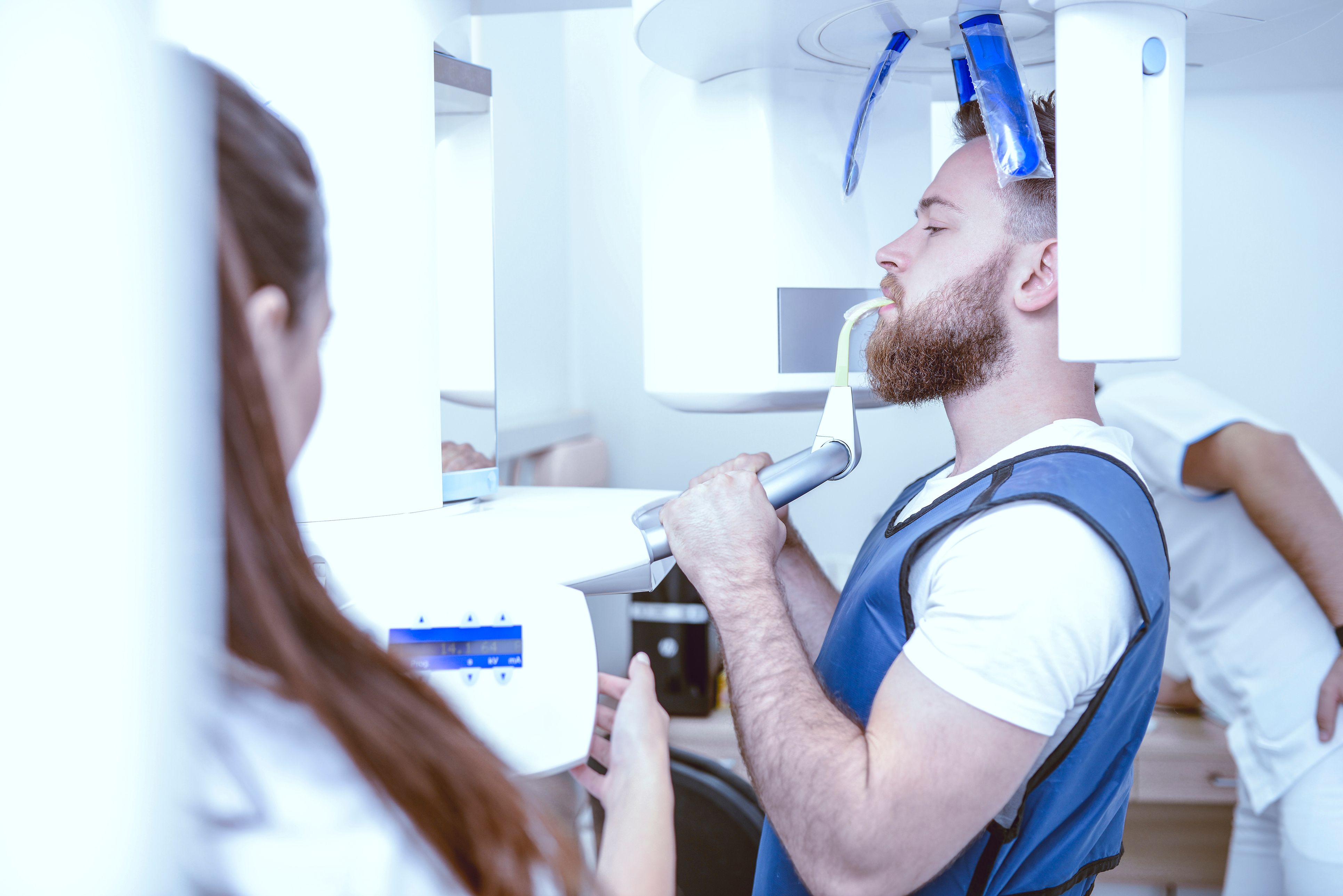 Image of a patient in an x-ray machine with his dentist.