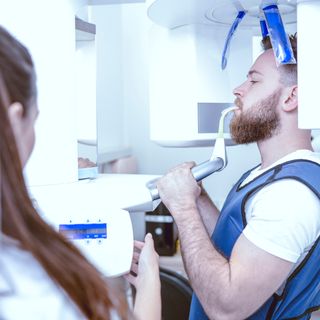 Image of a patient in an x-ray machine with his dentist.
