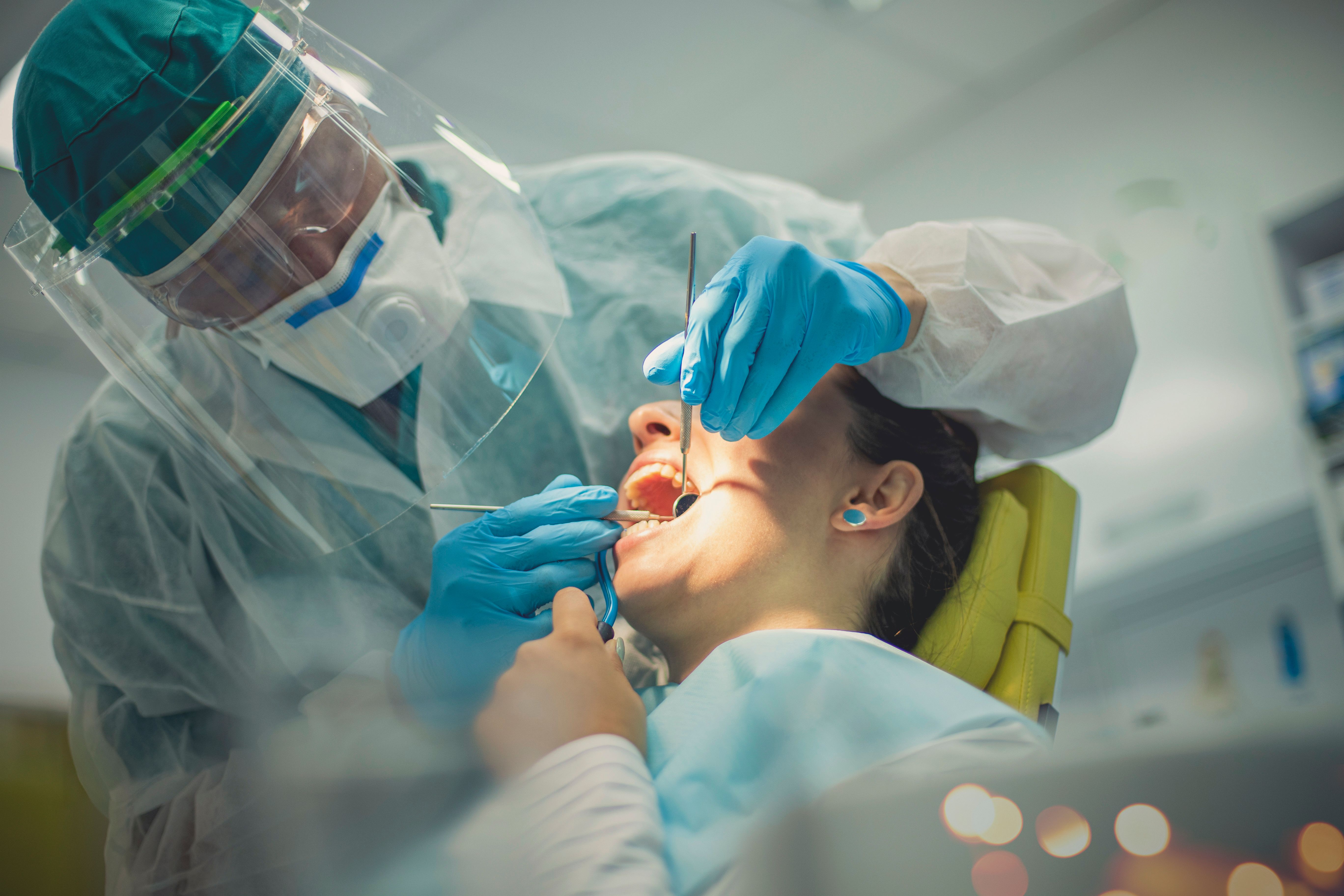 Image of a dentist inspecting an patient in a dental chair.