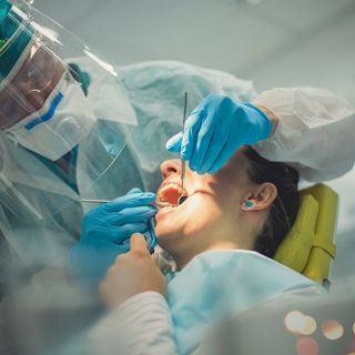 Image of a dentist inspecting an patient in a dental chair.