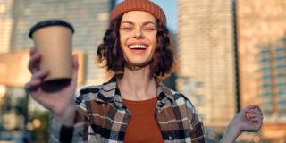 Image of a woman holding a cup of coffee during the morning sun rise.