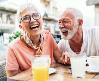 Image of an elderly couple enjoying breakfast with their white smiles.