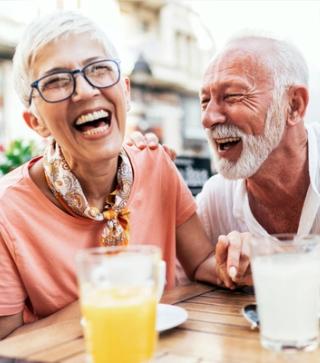 Image of an elderly couple enjoying breakfast with their white smiles.