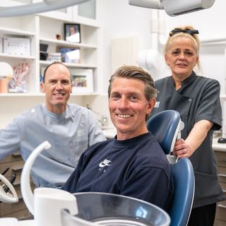 Image of Dr. Tim Nicolls with his dental assistant and his happy patient.
