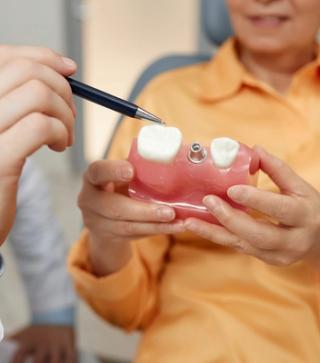Image of a dentist showing a elderly female how dental implants work.