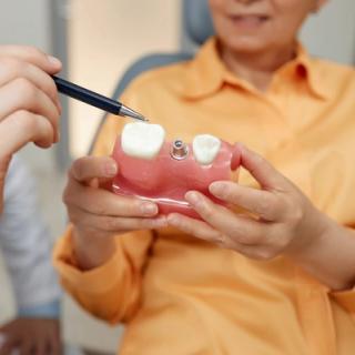A dentist demonstrating how a dental implant works to a patient.