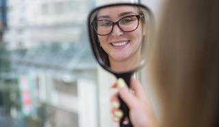 Image of a CBD Dental patient looking into the mirror seeing her bright white teeth.