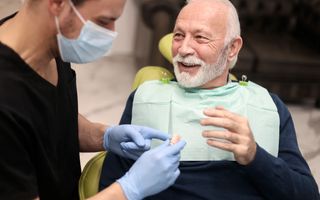 Senior male talking about dentures with his dentist