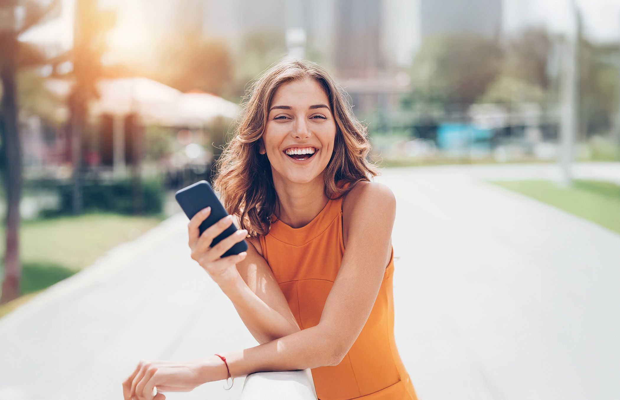 Image of female with her mobile phone, enjoying your newly whiten teeth.