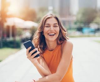 Image of female with her mobile phone, enjoying your newly whiten teeth.