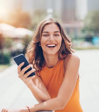 Image of female with her mobile phone, enjoying your newly whiten teeth.