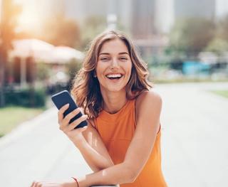 Image of female with her mobile phone, enjoying your newly whiten teeth.