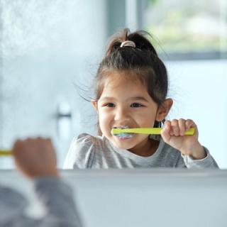 Image of a child brushing her teeth, maintaining her oral health at a young age.