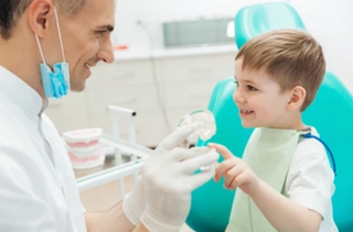 Image of a child with his dentist, showing the young child a mouthguard.