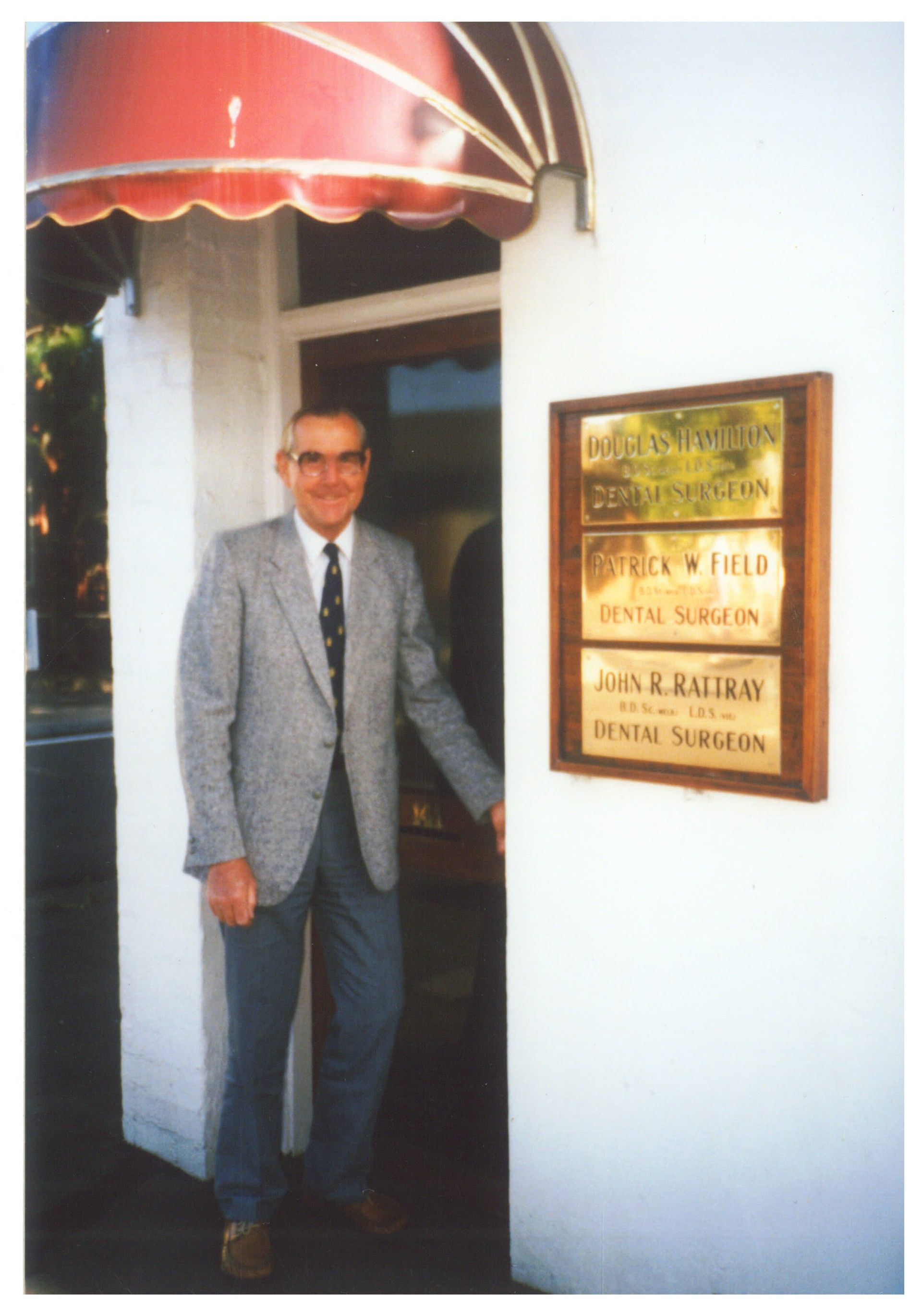Historical image of Dr Douglas Hamilton standing in front of his dental practice.