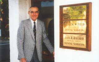 Historical image of Dr Douglas Hamilton standing in front of his dental practice.