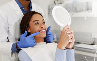 Image of a dental patient in a chair looking at her newly whiten teeth for the first time.