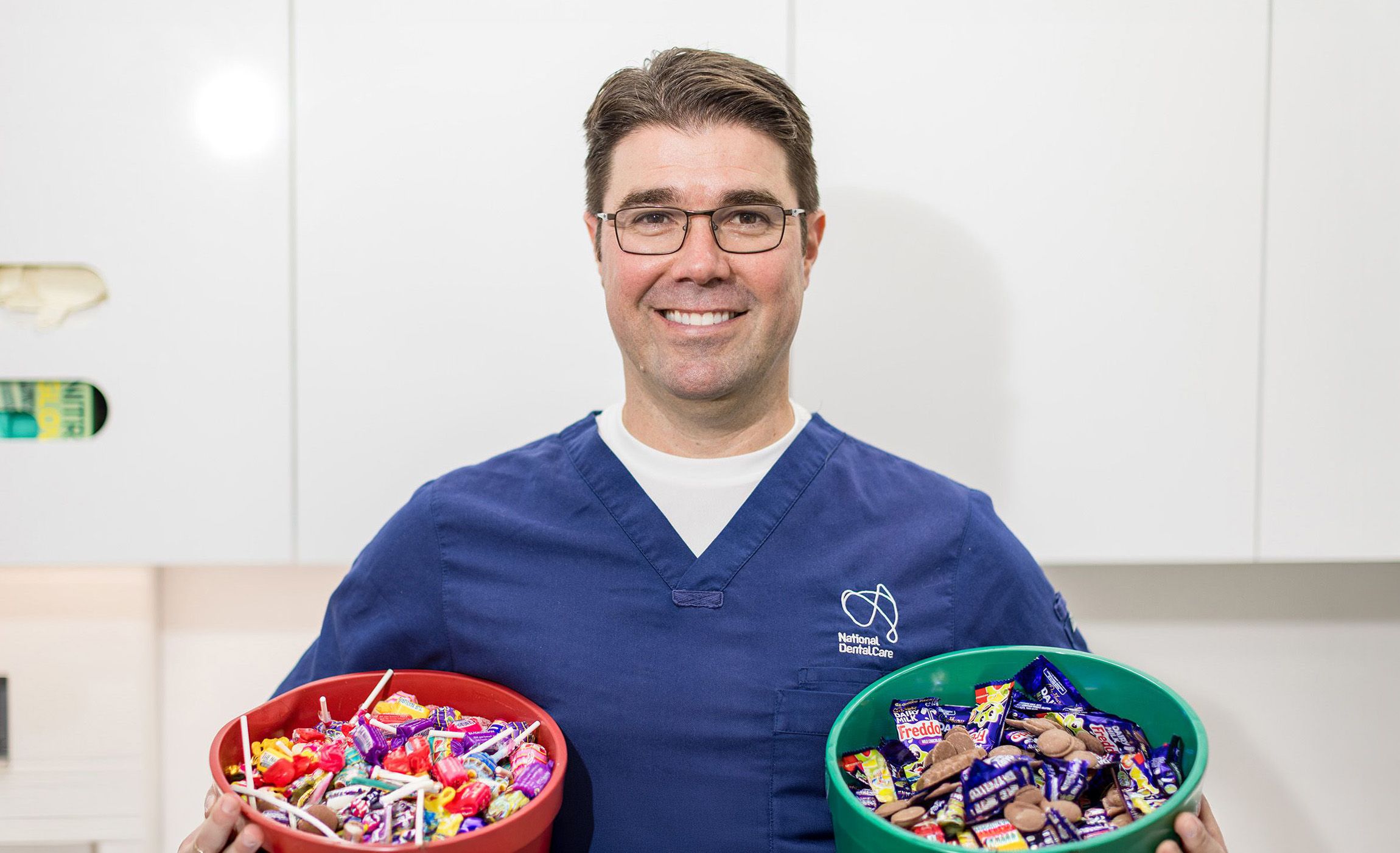 Dr Anthony Benedetto, Lead Dentist at NDC Erina, holding two buckets of chocolate and lollies.