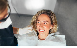 A female in a dental chair with a white, straight smile.