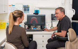 Image of our dentist, Dr Sam Guirguis smiling with his patient.