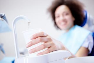 Image of a patient in a dental chair refilling her cup before a regular check-up.