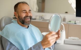 Smiling dental patient looking in the mirror