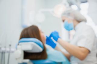 Image of a patient being inspected by a dentist on a dental chair.