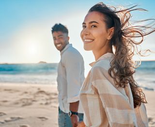 An image of a happy couple on a beach with their whitened teeth