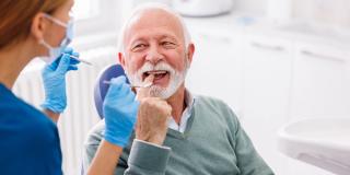 An elderly man discussing his dental issues with a dentist, Experience the benefits of dental implants.
