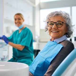 An elderly patient with her dentist going finishing off her dental examination.