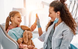 Image of a child high-fiving a dentist.