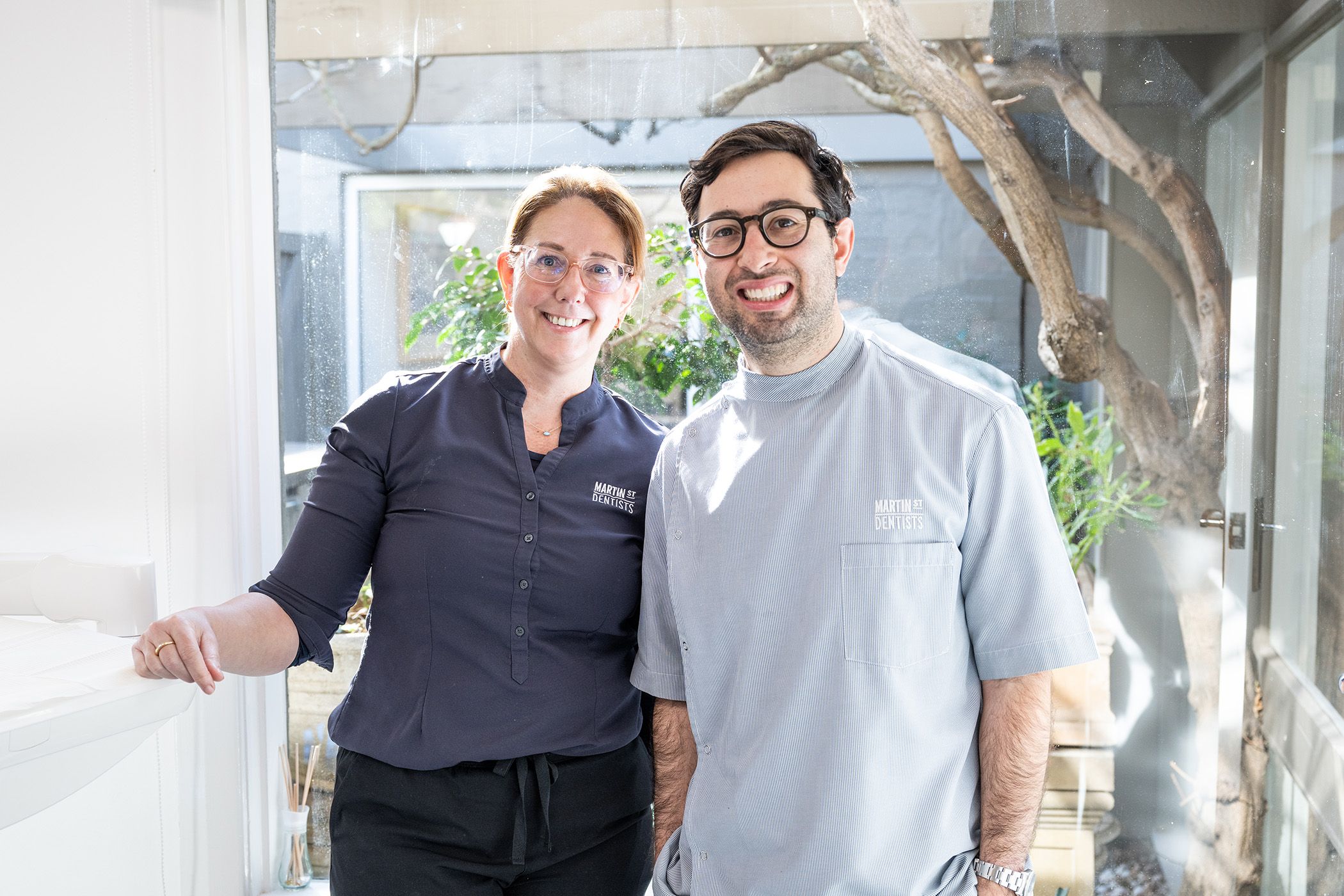 Image of Dr. Adam Sibio with a receptionist staff member, both showing their bright smiles.