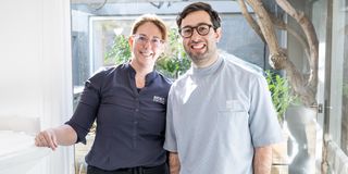 Image of Dr. Adam Sibio with a receptionist staff member, both showing their bright smiles.