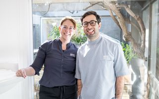 Image of Dr. Adam Sibio with a receptionist staff member, both showing their bright smiles.