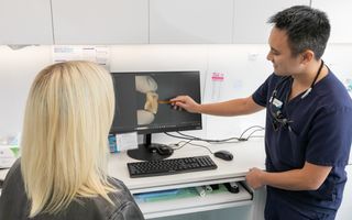 Image of a dentist with his patient going through her teeth scans.