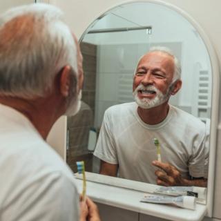 Image of a elderly patient cleaning his dentures at home.