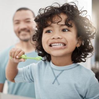 Image of a child practicing how to brush his teeth for good dental habits.