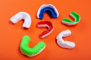 Image of a 6 mouthguards with an orange background.