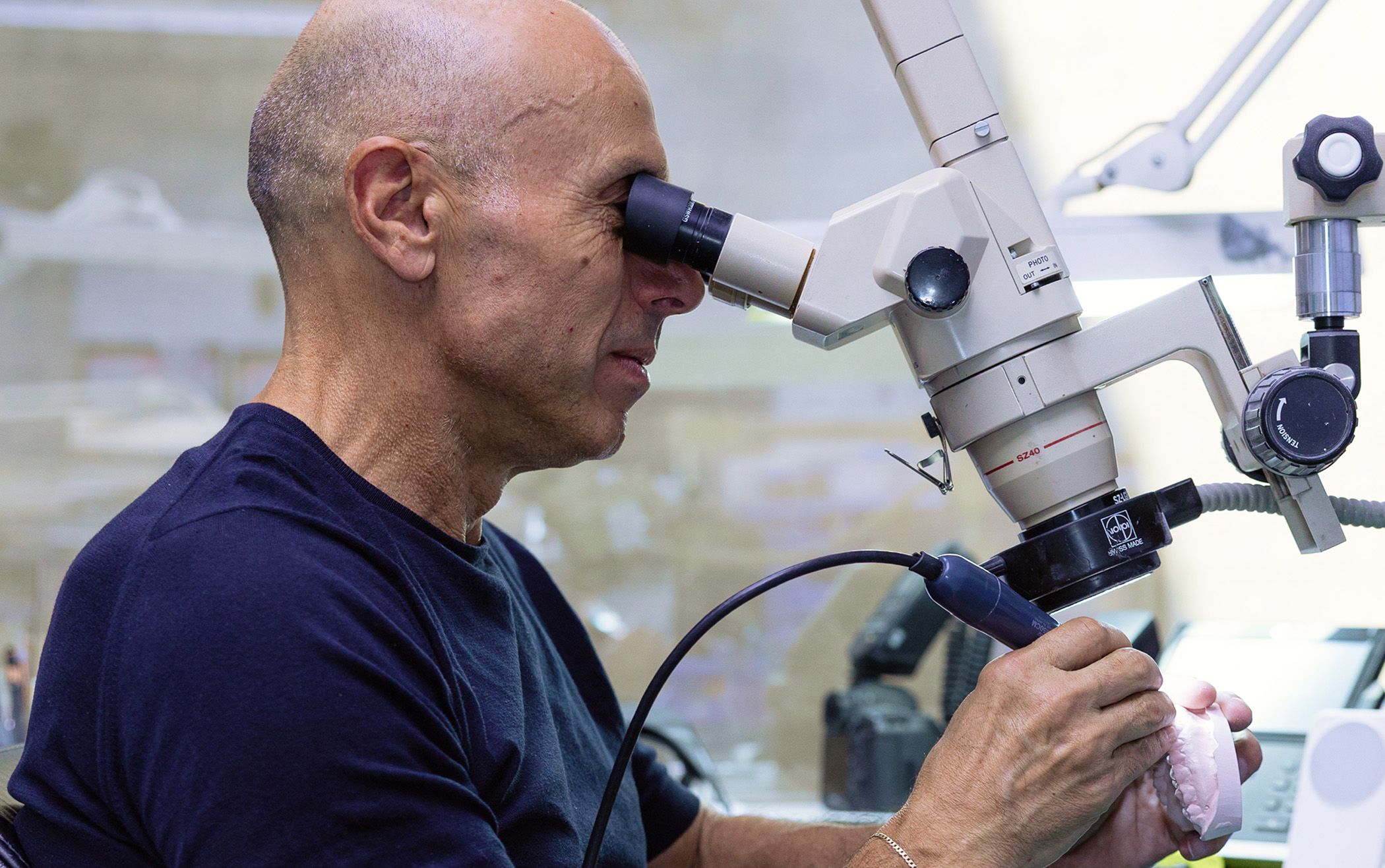Image of our dentist using a microscope to perform dental work.