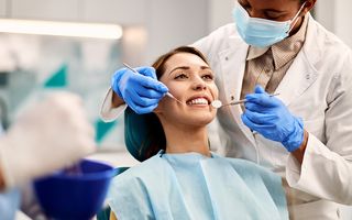 Image of a patient in a dental chair being examined by a dentist.