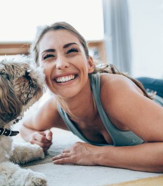 Female having fun with her dog and her new white teeth at home
